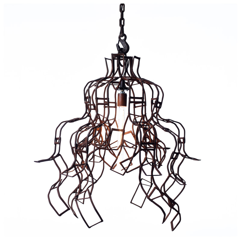 Simplistic suspended artistic light with single long bulb made from rust colored scrap metal welded into strands cascading down from the top. Created by Lucy Slivinski.