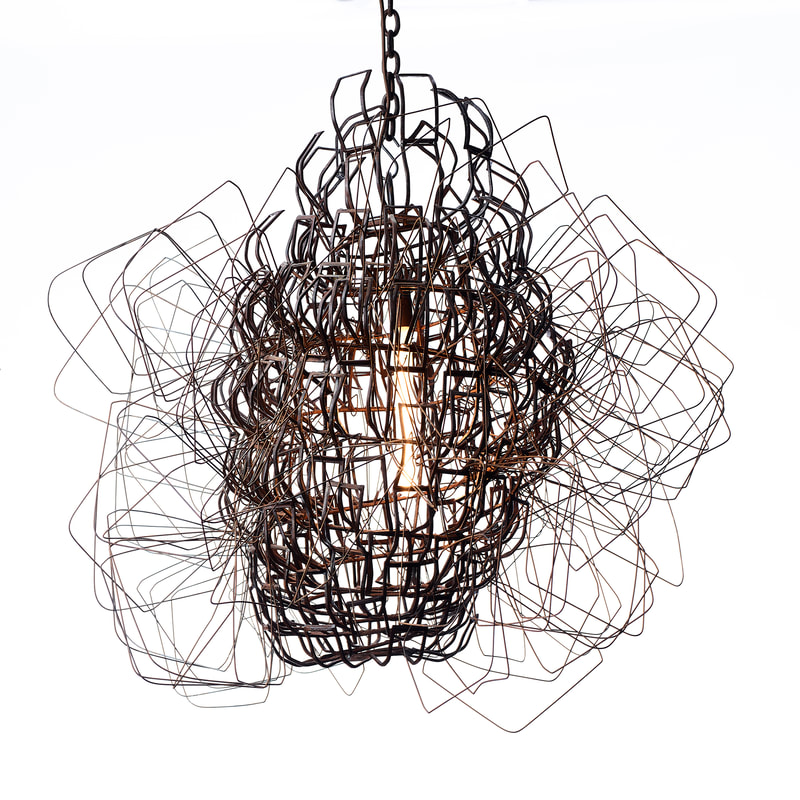 Suspended artistic lighting made from pieces of rust colored scrap metal welded to form a bulbous shape encasing a single long bulb inside. Stretched coat hangers are woven around the form, protruding outward in all directions. Created by Lucy Slivinski.