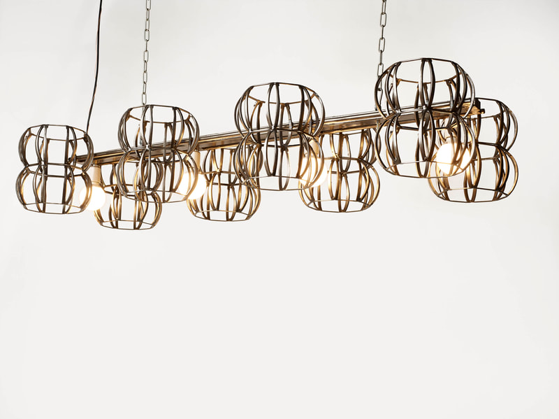 Long suspended sculptural lighting created by Lucy Slivinski with four bulbs in a line and spherical metal frames perpendicular to each bulb on both sides. 