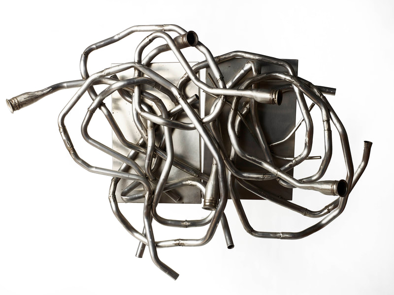 Abstract wall mounted sculpture made from salvaged stainless steel tubes and panels. Created by Lucy Slivinski. 