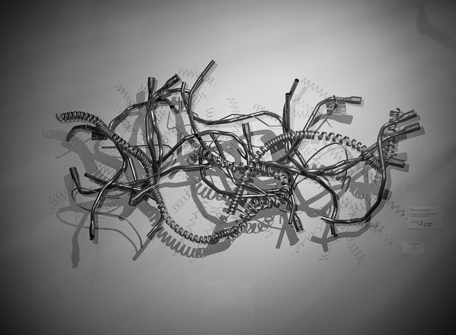 Wall mounted abstract metal sculpture made from salvaged stainless steel tubing and coils. Created by Lucy Slivinski. 