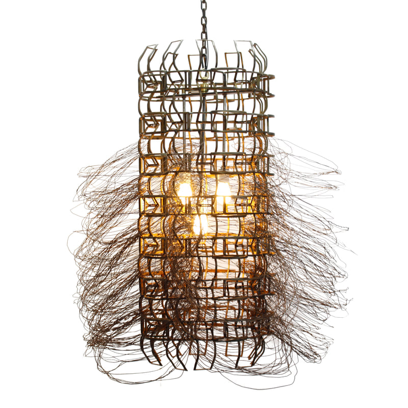 Long suspended artistic light with three bulbs central to a cylindrical rust colored metal frame with wire woven around looping down and out from the piece. Created by Lucy Slivinski.