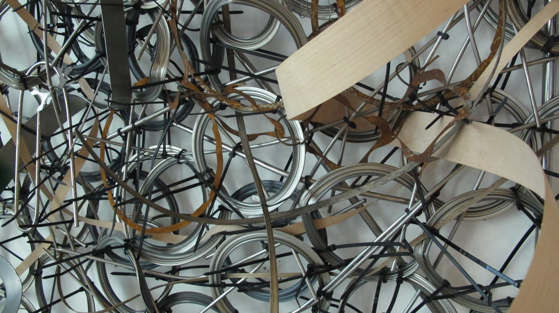 Close up shot of paint can rings, black zip ties and strips of wood and metal woven in. Created by Lucy Slivinski. 