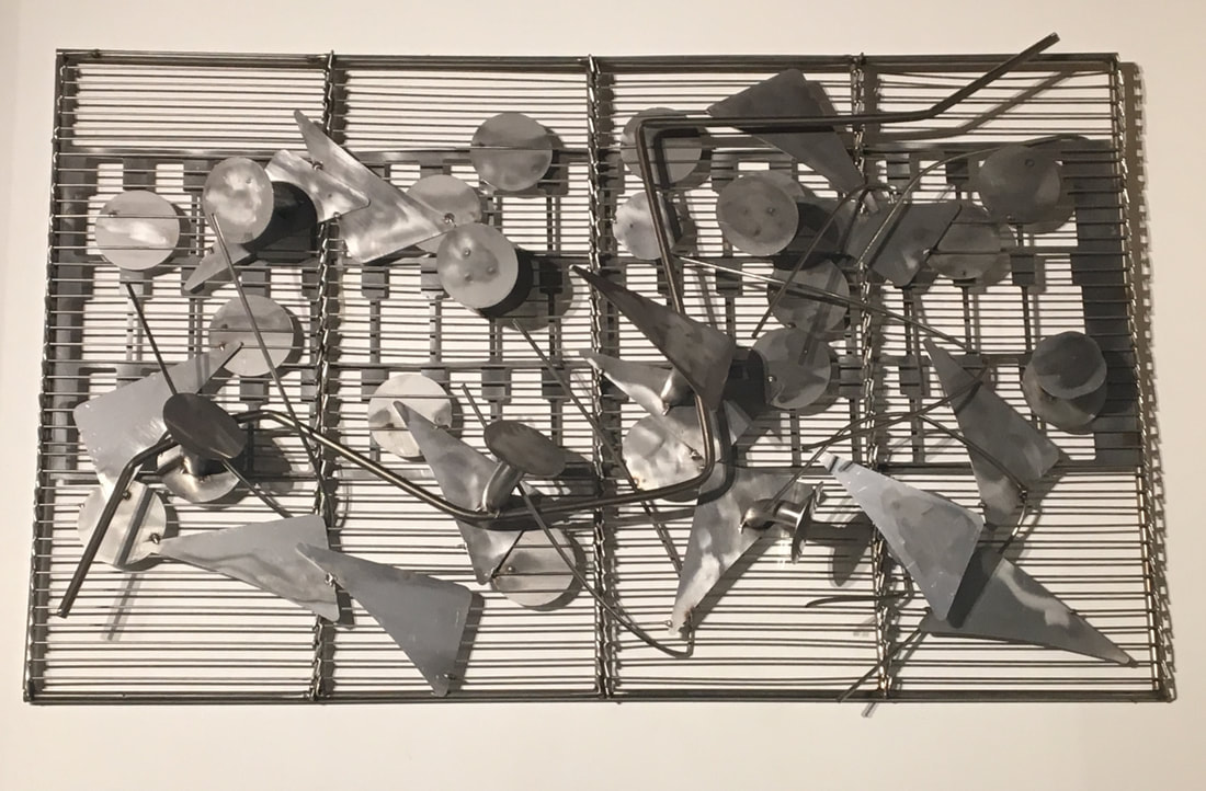 Wall mounted abstract metal sculpture made from salvaged stainless steel cut outs mounted onto metal frame. Created by Lucy Slivinski. 